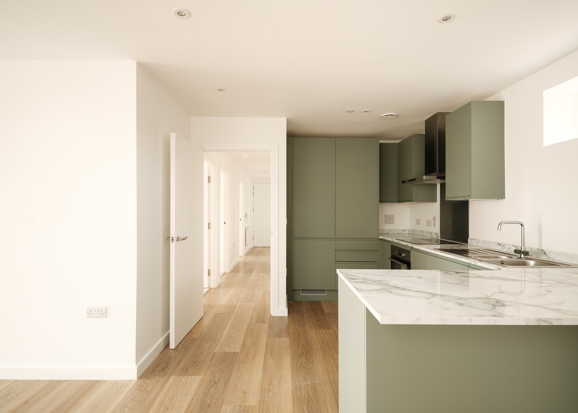 view of Farmstead Road, a brick residential complex in south london by metropolitan workshop. it features green gardens and orange metal details such as window frames and balconies
