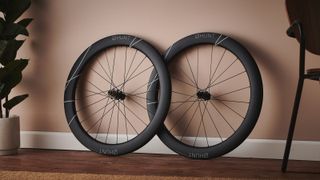 A pair of Hunt Limitless Aero 60 Disc road bike wheels leans against a terracotta wall