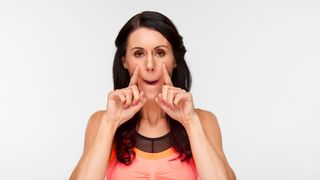 Woman performing the cheek and jaw lift face yoga exercise