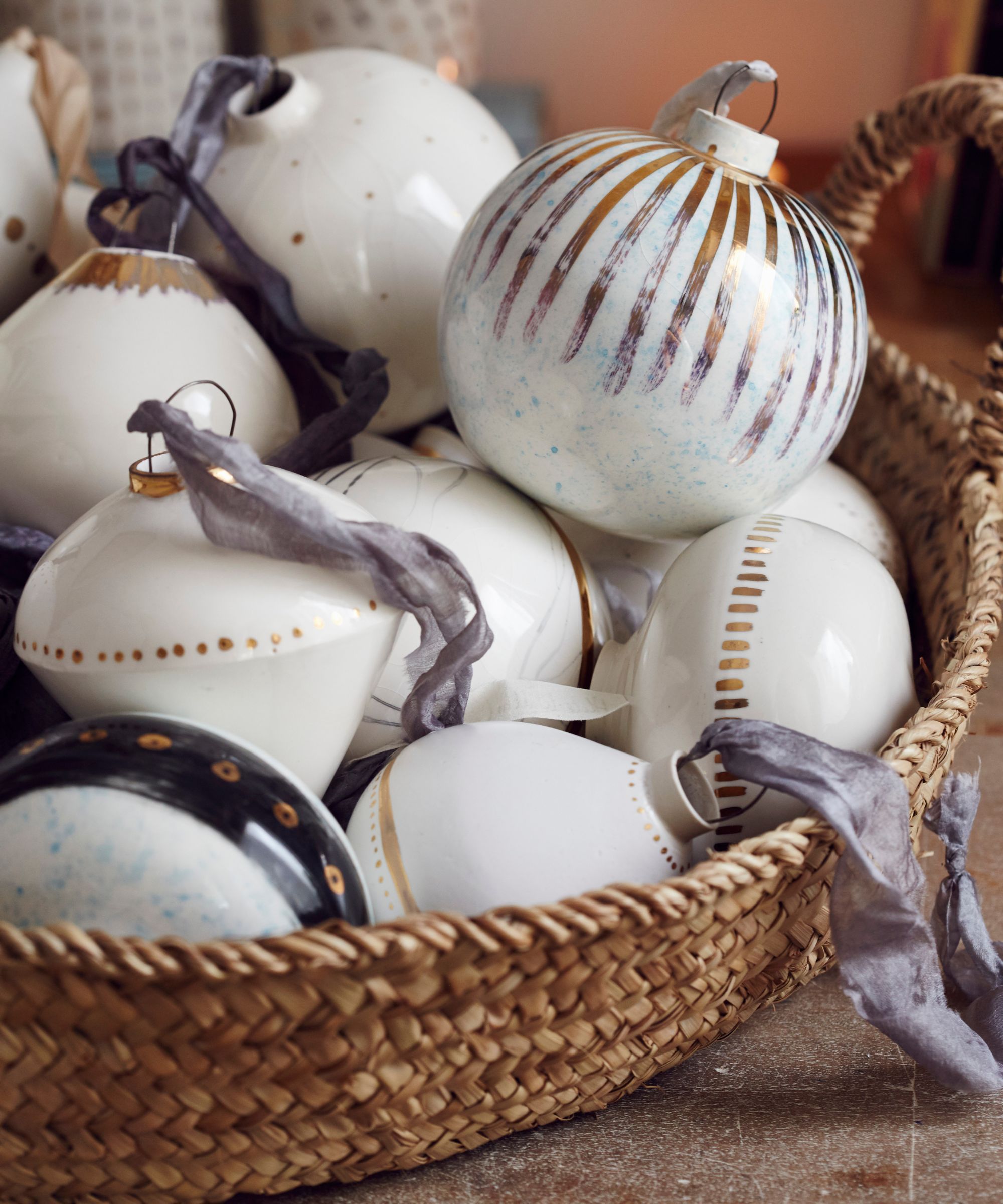 A wicker bowl of white and gold ceramic Christmas tree ornaments.