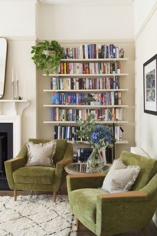 Living room with green velvet chairs and bookcase