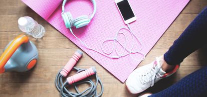 activewear accessories - Low Section Of Woman With Exercise Equipment Sitting On Hardwood Floor