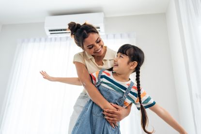 Woman and child hugging in front of air conditioning unit
