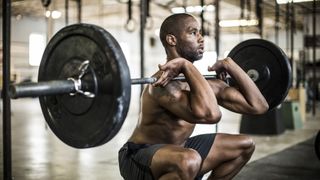 Man doing a barbell front squat in a gym