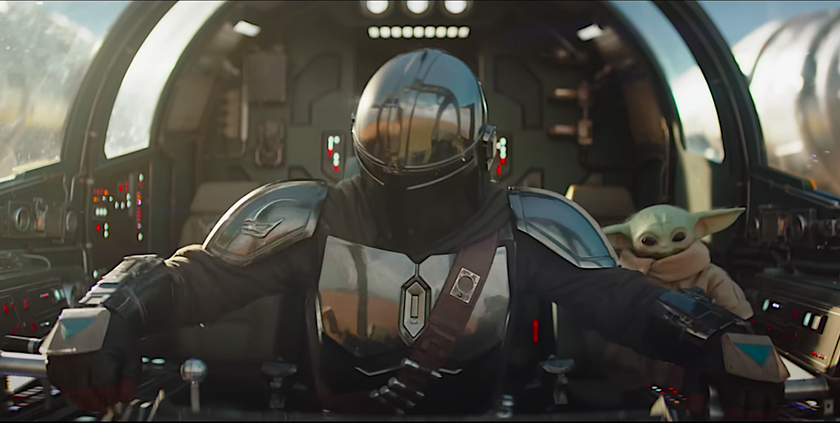 a helmeted space pilot with a baby green alien in a spaceship