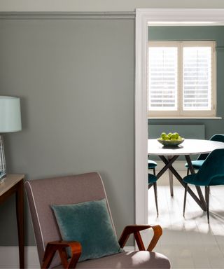 living room painted with gray-green walls and neutral armchair with teal cushion