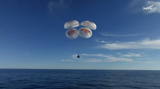 The Dragon crew capsule deploys parachutes in preparation for splashdown