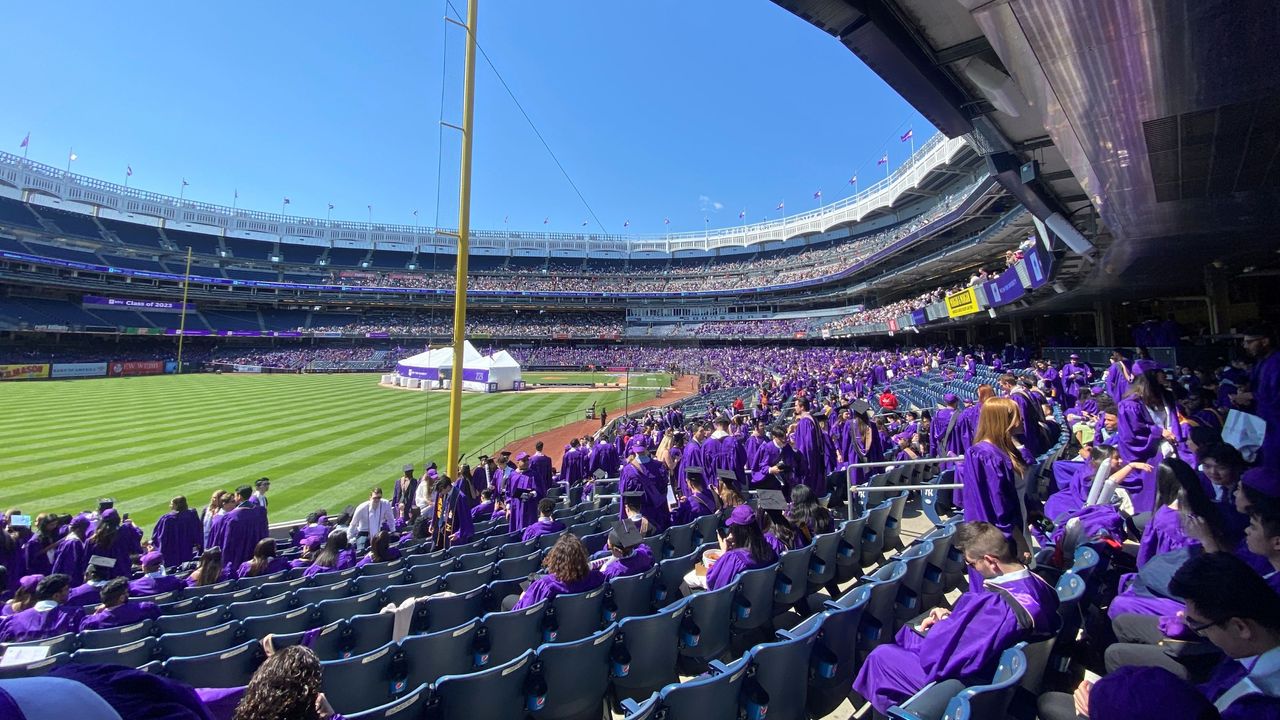 Students in purple robes at Yankee Stadium for NYU&#039;s 2023 commencement ceremony. 