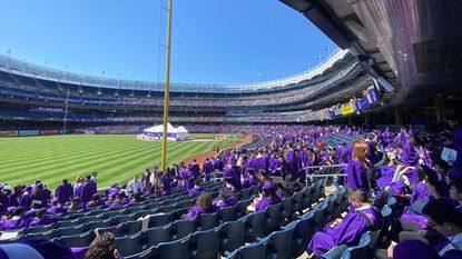 Students in purple robes at Yankee Stadium for NYU's 2023 commencement ceremony. 