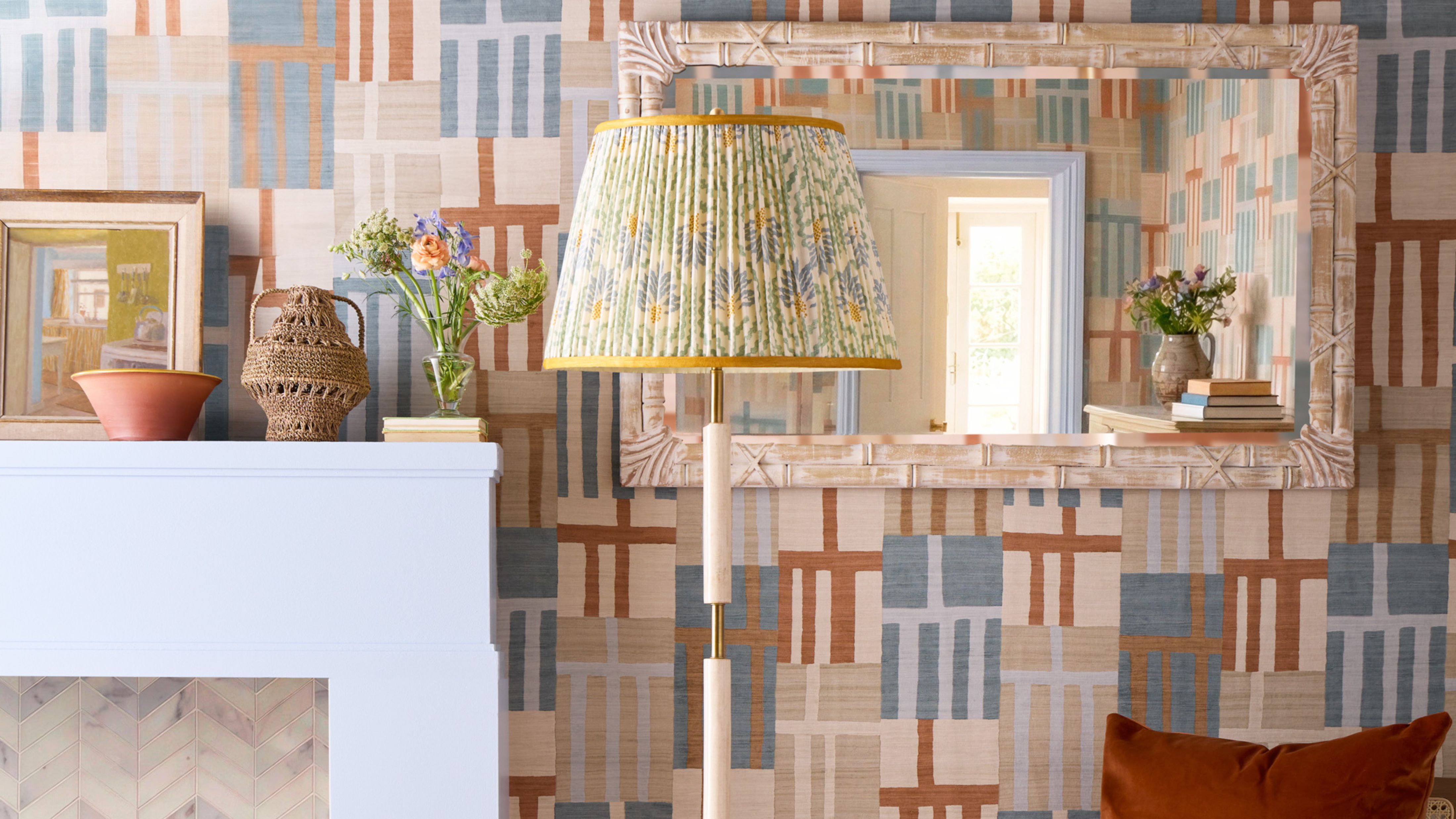 Pattern-filled living room featuring geometrically printed wallpaper and a floral print pleated lamp