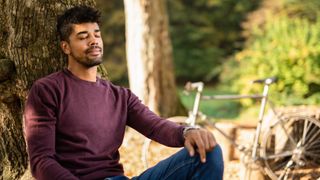Man with eyes closed breathing deeply in nature