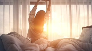 Woman stretching in her bed at sunrise