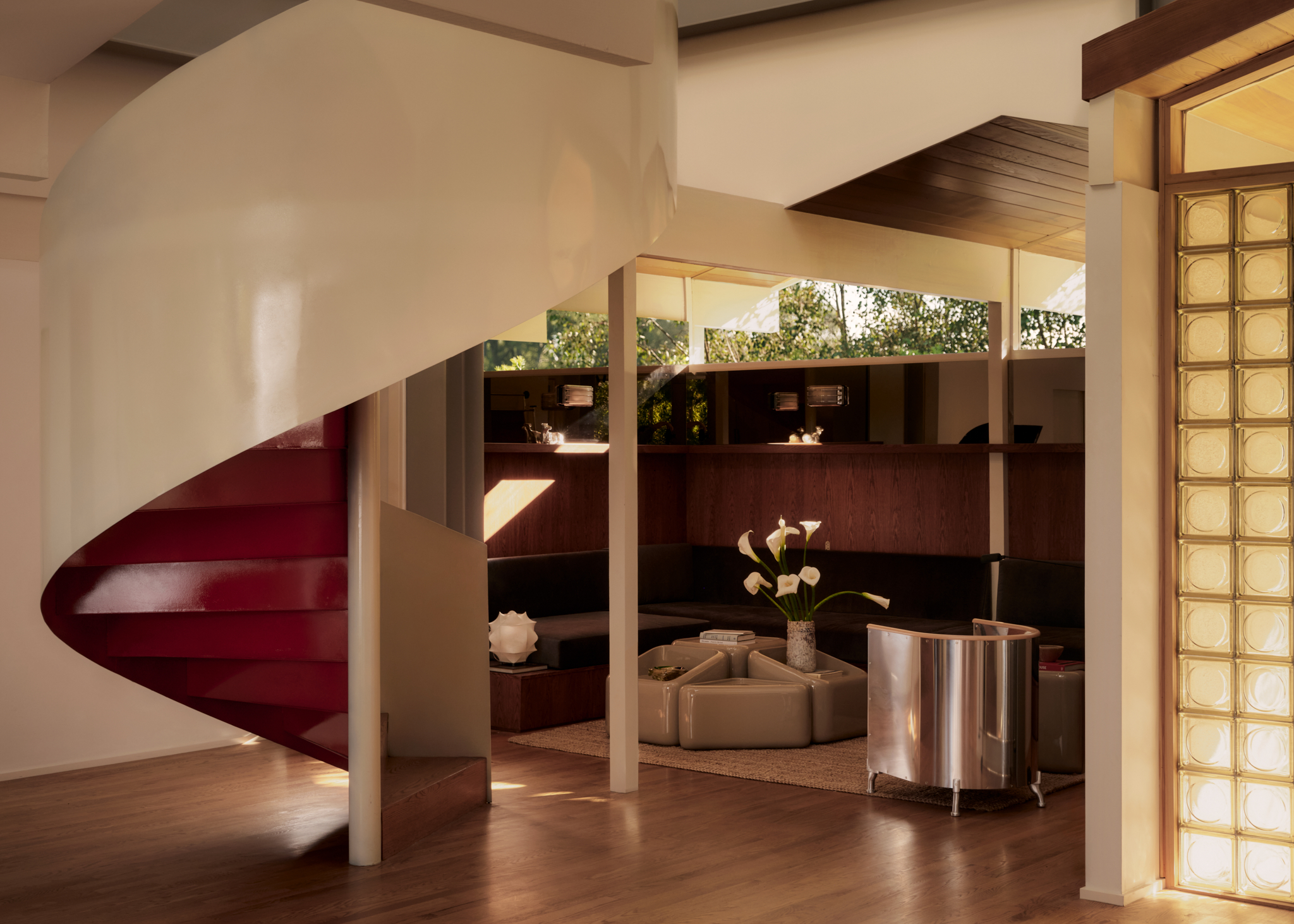 Spiral staircase and view of den area with seating with red lacquer accents and glass blocks next to the front entrance