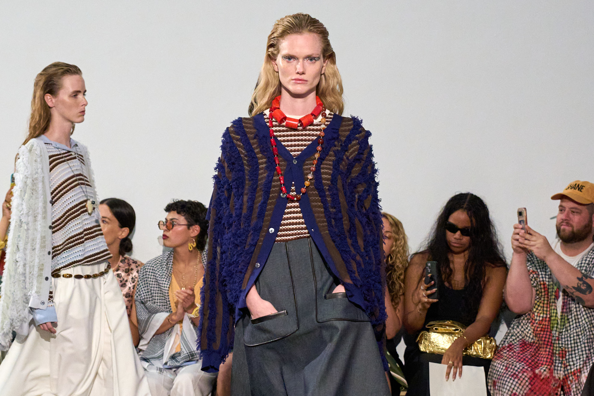 a model walking down the runway at Zankov wearing a striped tee and semi-sheer blue sweater
