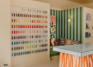 a wall of color swatches, a seating area and a skirted table in a fabric showroom