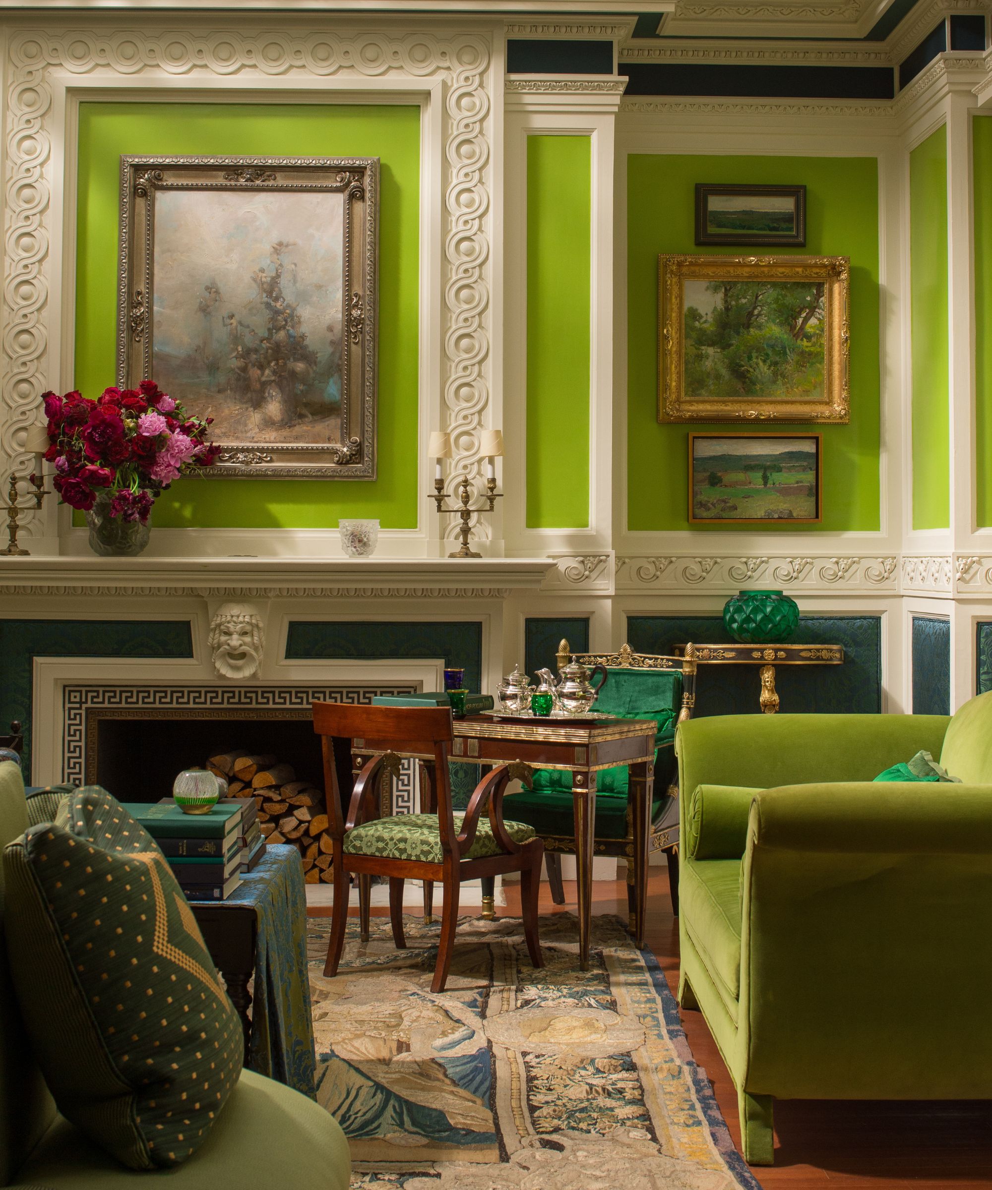 Living room with lime green walls, fireplace, antique carpet, green velvet sofa, mahogany games table and chairs in the corner.