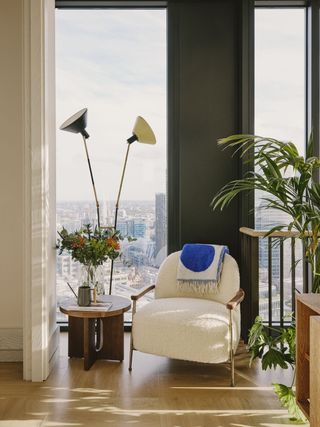 white chair with plants around it and window behind looking out onto london skyline