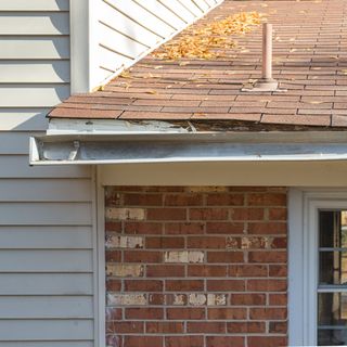 Loose white gutter on a red bricked house