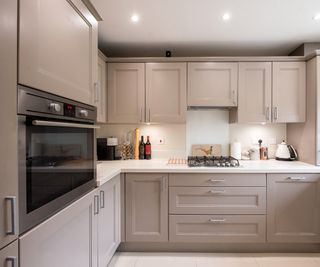 A general interior view of a small truffle taupe coloured shaker style fitted kitchen with kitchen cabinets