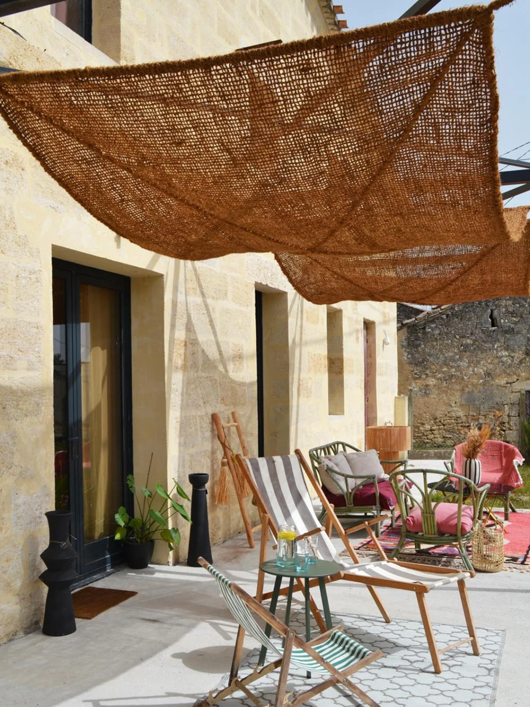 A coconut fiber shade sail from Boutique Boheme over garden chairs in an outdoor living room