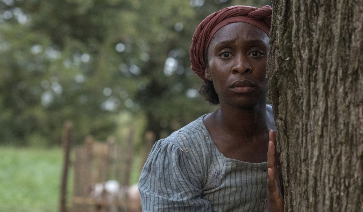 Cynthia Erivo standing behind a tree as Harriet Tubman in Harriet.