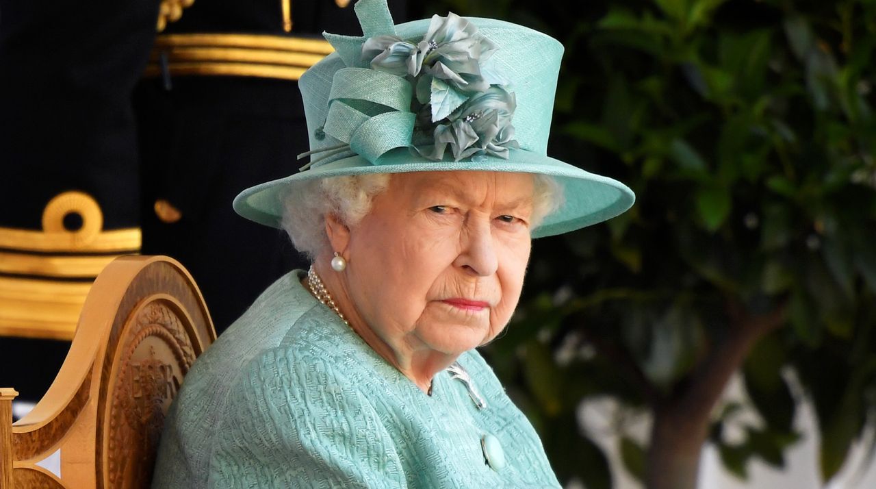 Queen Elizabeth glares while wearing a green suit and matching hat