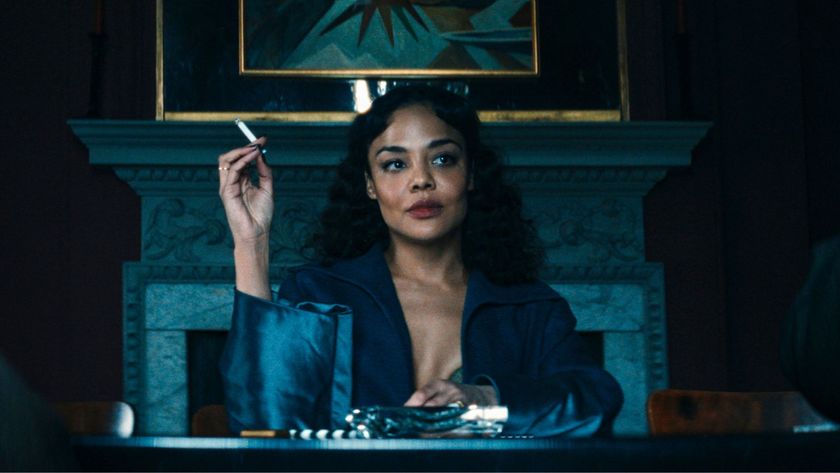Tessa Thompson sits at a table smoking a cigarette