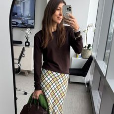 Woman in brown sweater and plaid skirt