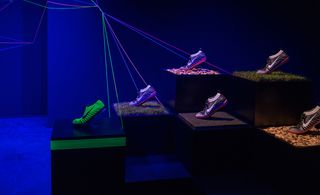 New Nike running shoes are displayed in a dark room with a spotlight on them.
