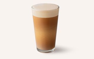A glass of Starbucks Nitro Latte; a brown coffee with white milk foam