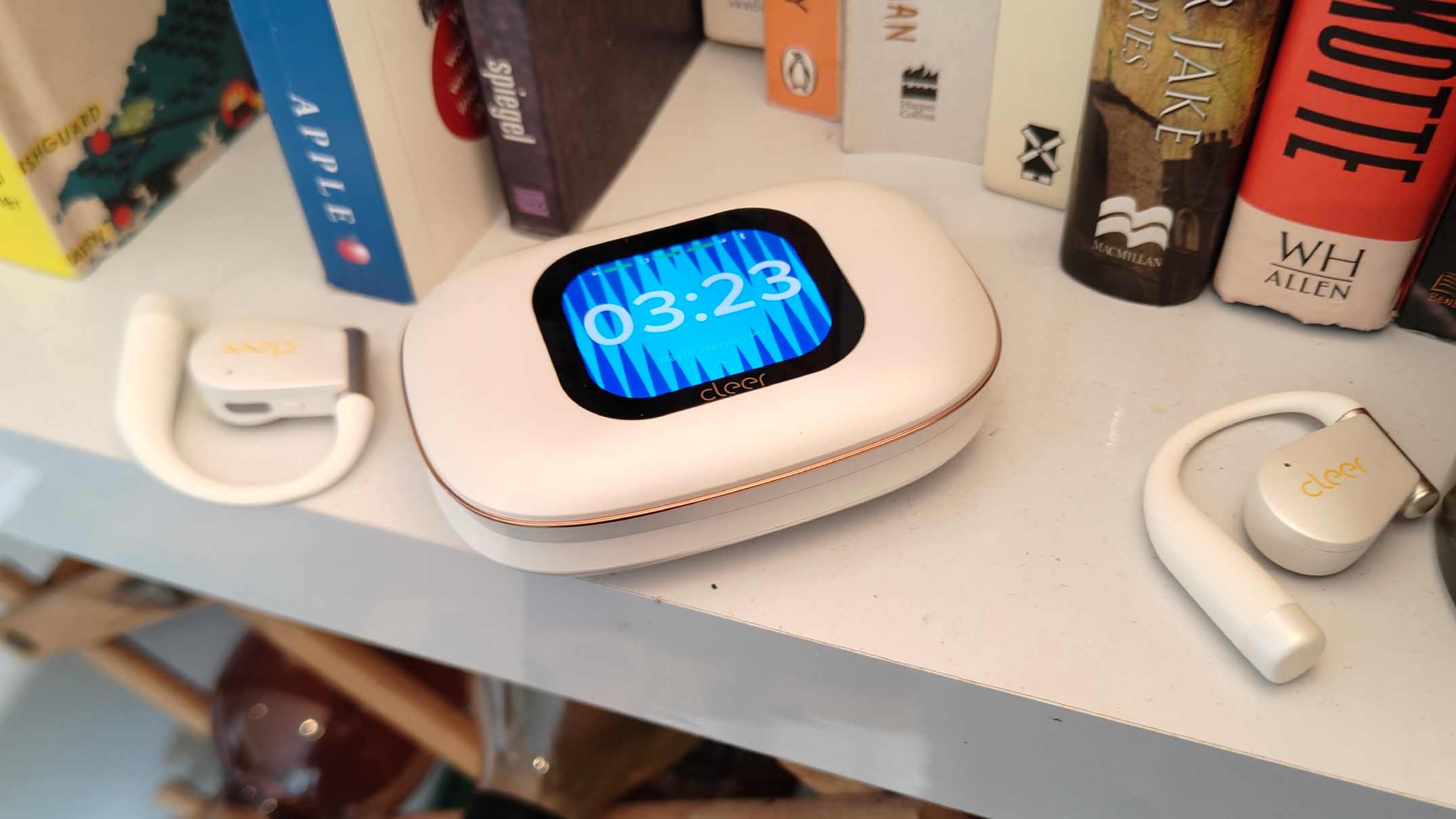 The Cleer Arc 5 buds on a shelf, either side of its case.