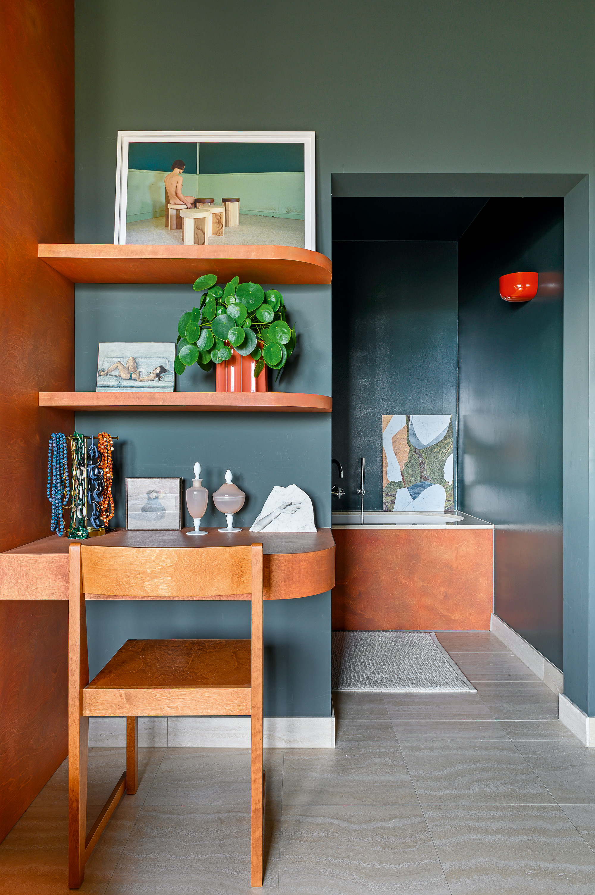 Dressing area with curved built-in desk and shelves, wooden chair, teal walls and red wall light