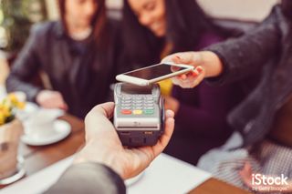 Woman making contactless payment with smartphone, by martin-dm