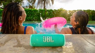 The JBL Flip 6 on the deck of a pool.