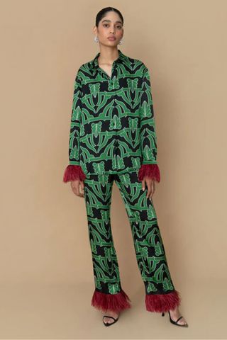 best party outfits - woman wearing patterned green co-ord with red feather trim on wrists and ankles