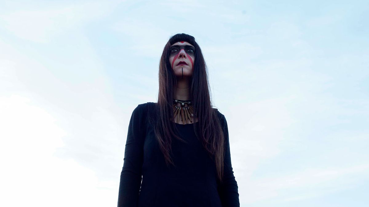 Lili Refrain portrait with warpaint against a blue sky 