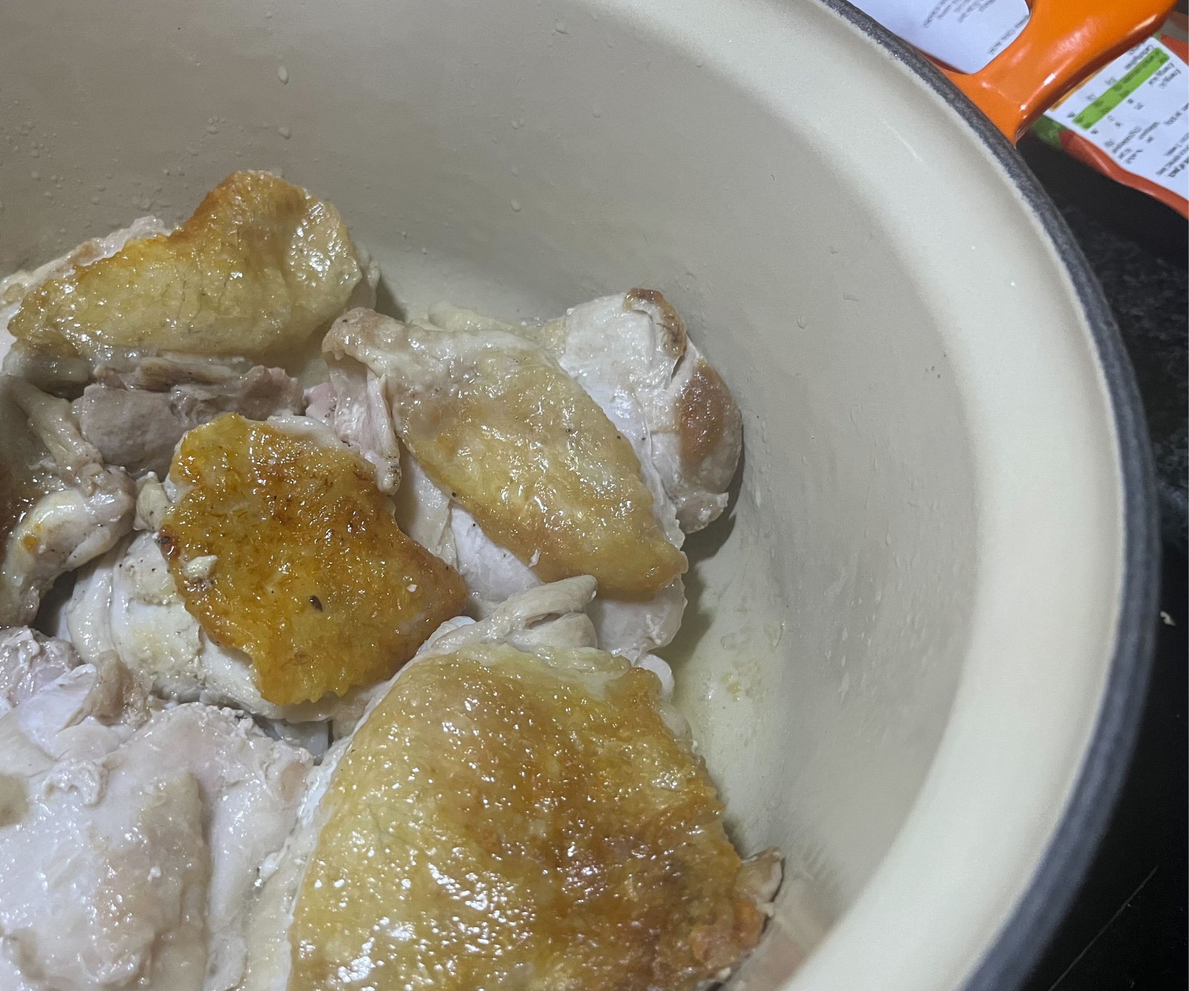 Golden brown chicken thighs in a enamel cast iron Dutch oven