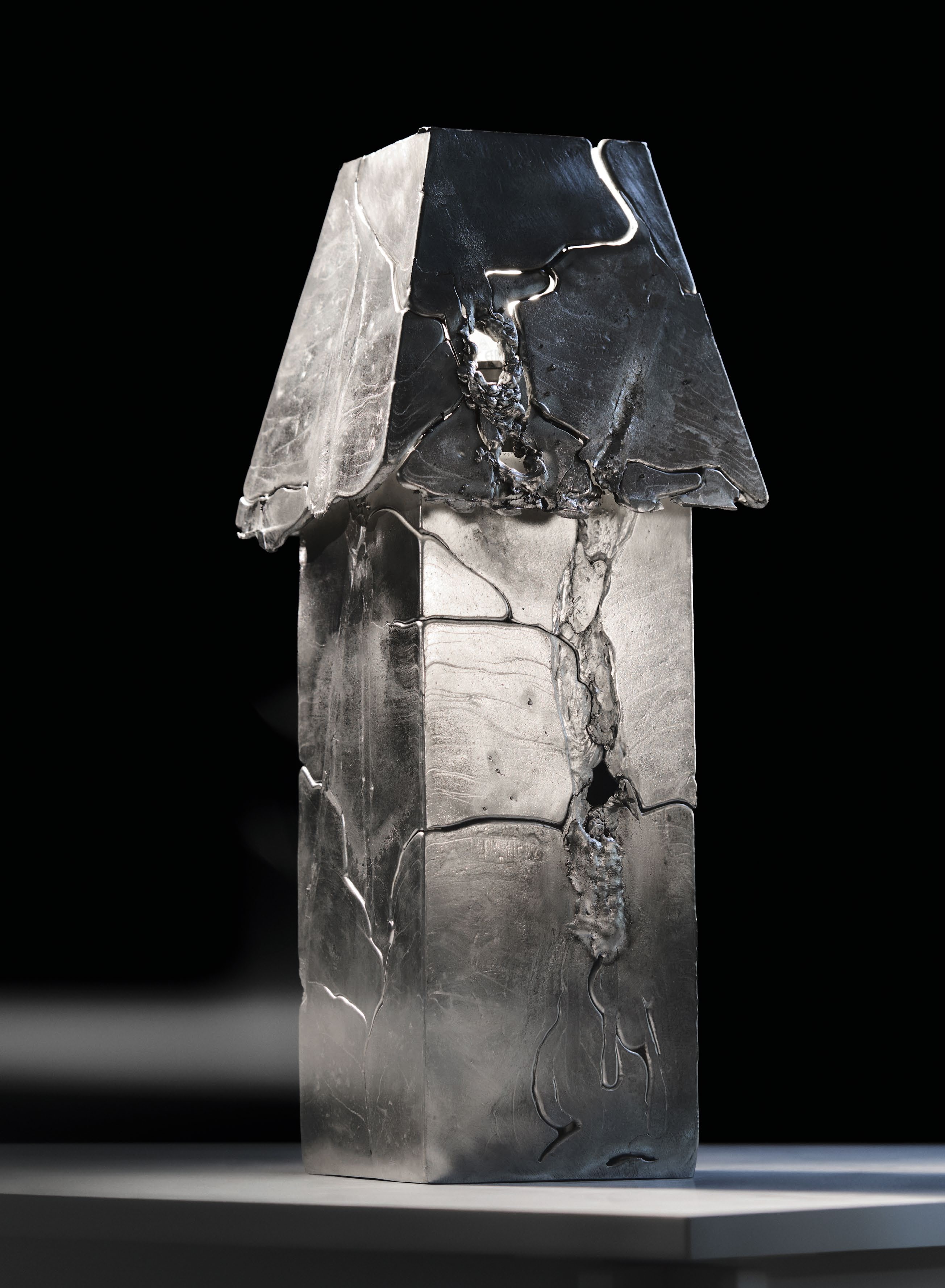 A sculptural lamp made of cast aluminum, featuring a chaotic yet intentional design, reflecting the unpredictable nature of life, showcased in an article about material alchemists.