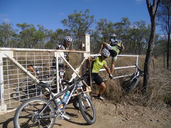 Michal Kafka (Bernard Rocky Trail Racing), Jessica Douglas and Ondrej Slezak (Bernard Rocky Trail Racing) scramble over the cattle gate