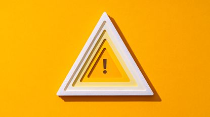 A triangle outlined in white with an exclamation point in the center against a yellow background.