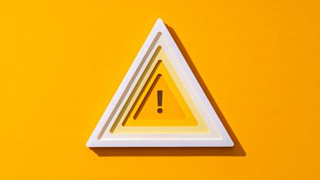 A triangle outlined in white with an exclamation point in the center against a yellow background.