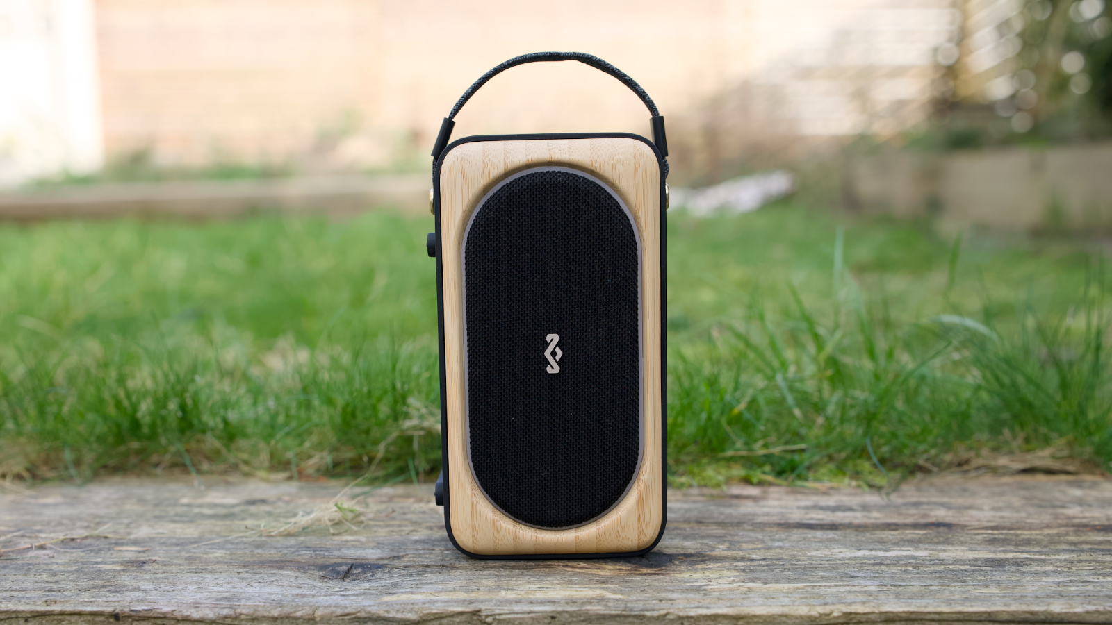 House of Marley Roots Solar Bluetooth Speaker outside on a wooden sleeper in a garden