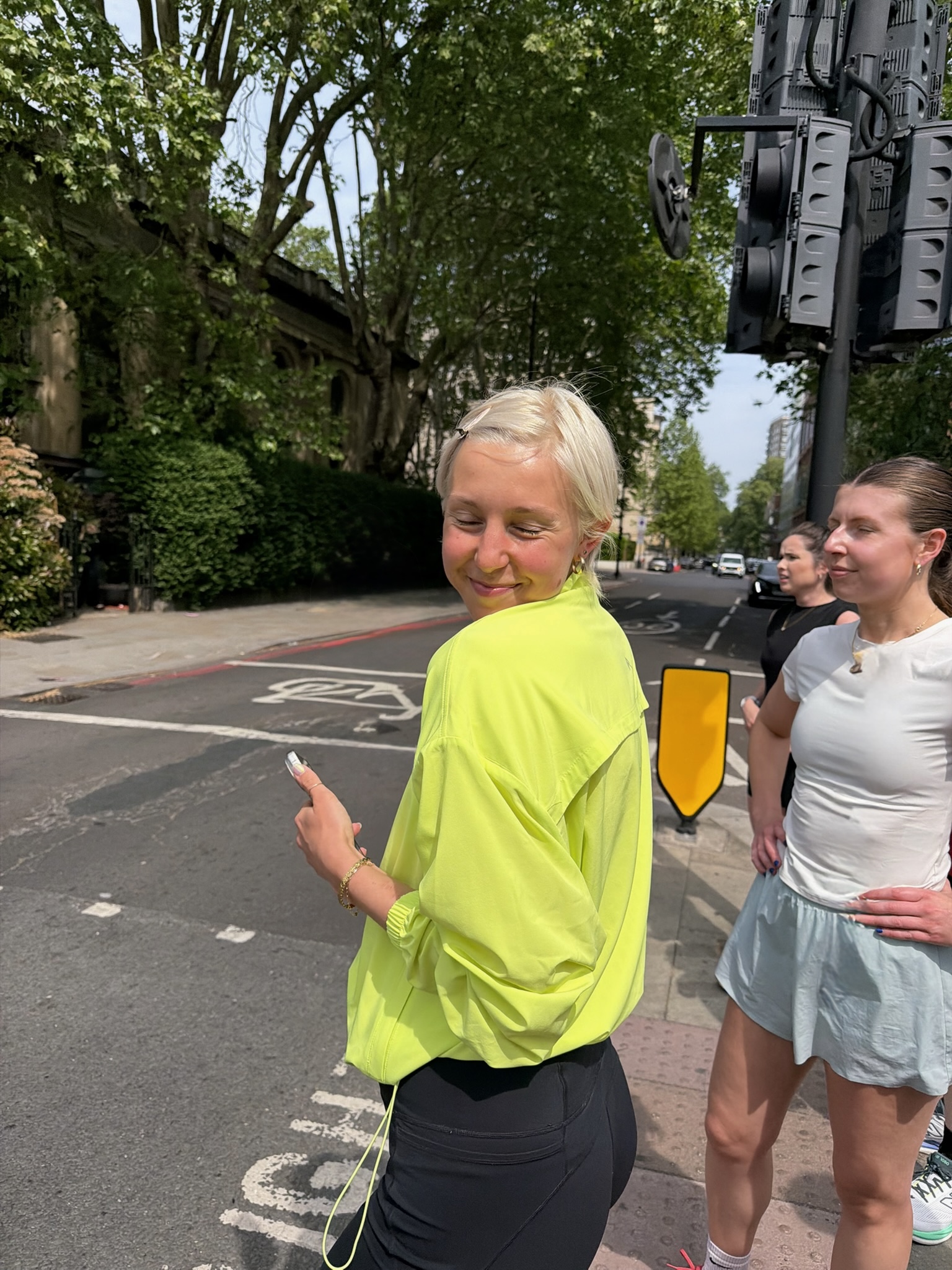 A female runner standing at traffic lights in a bright yellow running jacket