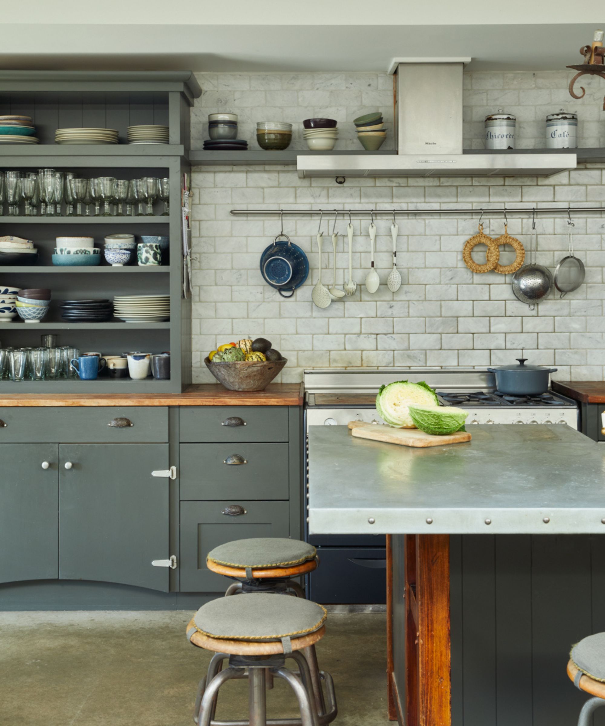 Retro kitchen with a kitchen island with a zinc countertop and vintage lab stool bar stools