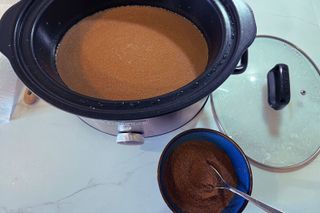 Slow cooker with lid with hot chocolate powder in a bowl