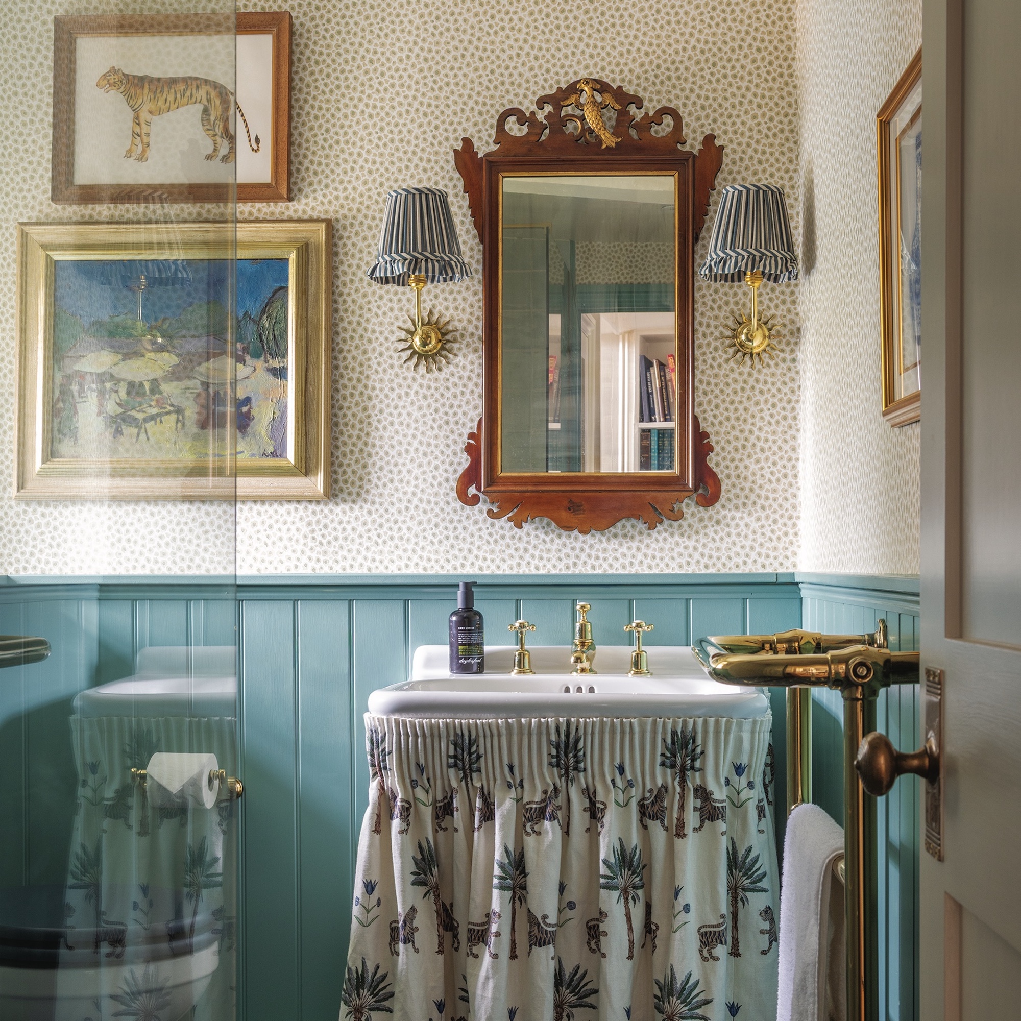 bathroom with half panelled walls painted blue, a sink with sink skirt and ornate mirror above
