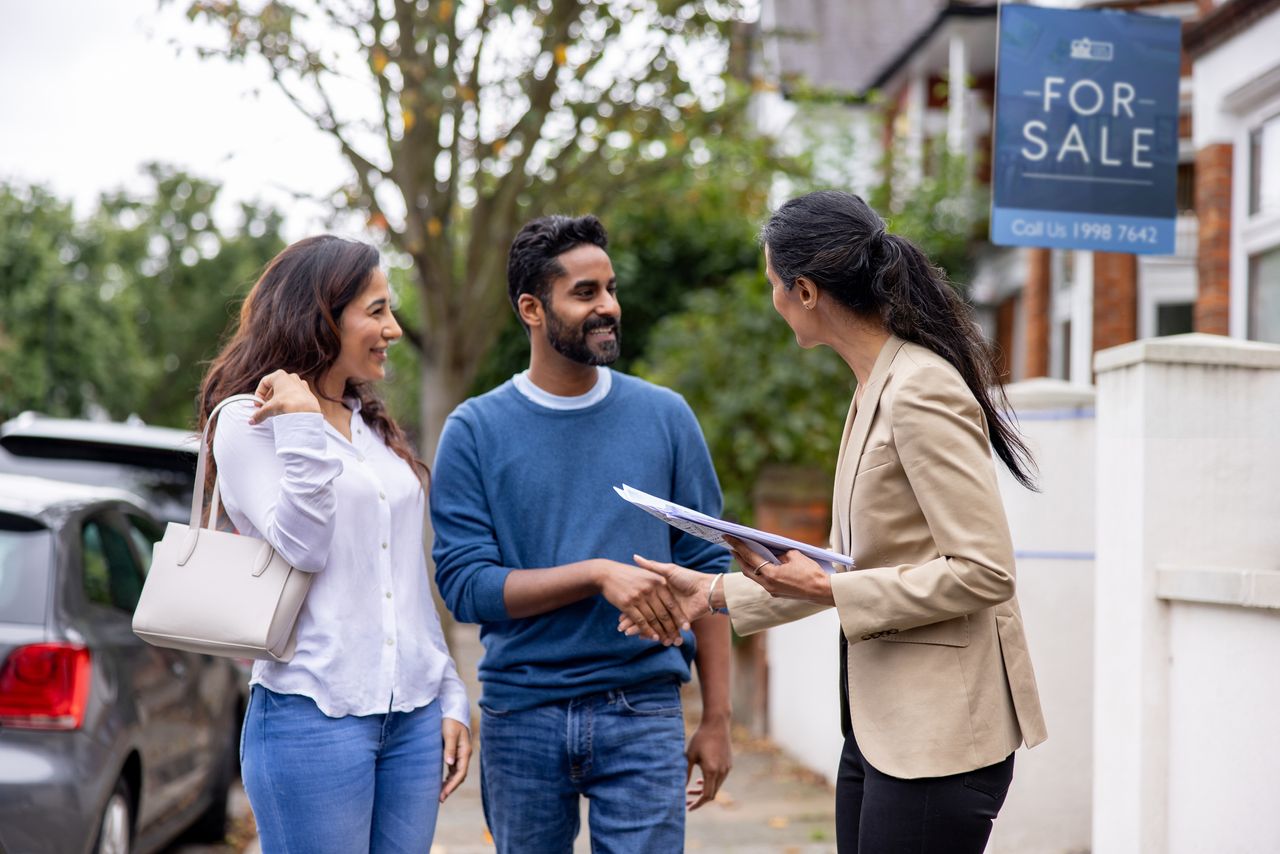 Couple greeting an estate agent in the street for a house showing