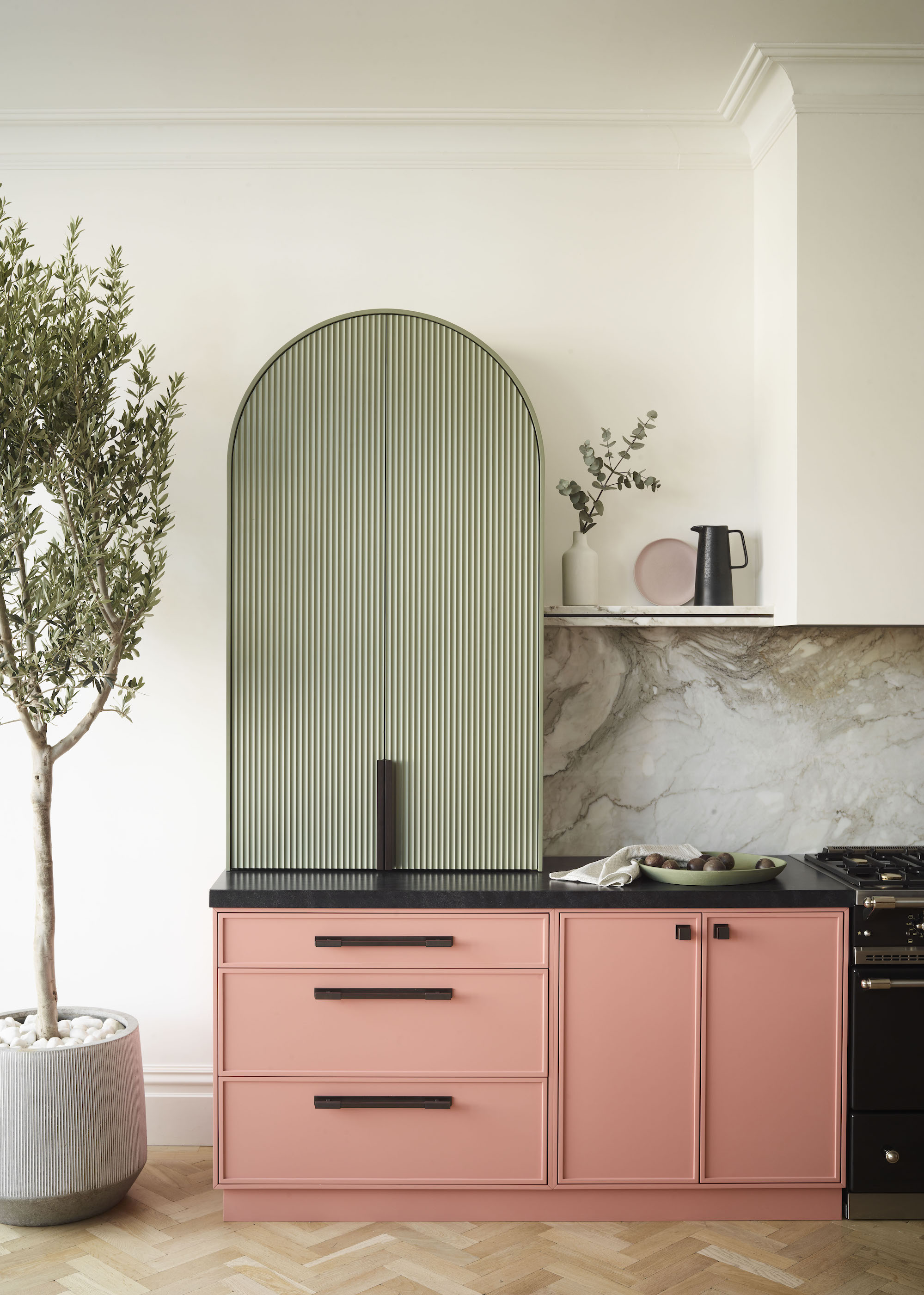 pink and green kitchen with marble splashbacks and wood parquet floors