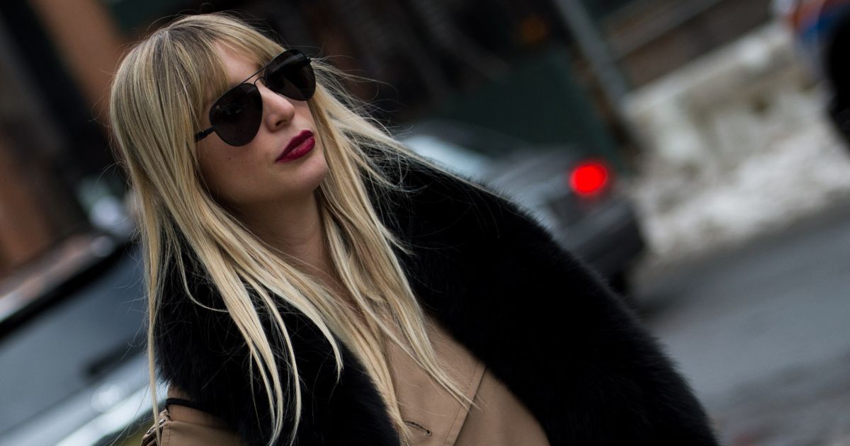 woman with long blonde hair walking through the cold street of new york with a fur scarf and sunglasses - la mer moisturising cream