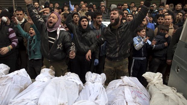 Syrians shout slogans as they gather around the shrouded bodies of civilians, who were executed and dumped in the Quweiq river, during their funeral outside the Yarmuk school in the Bustan al